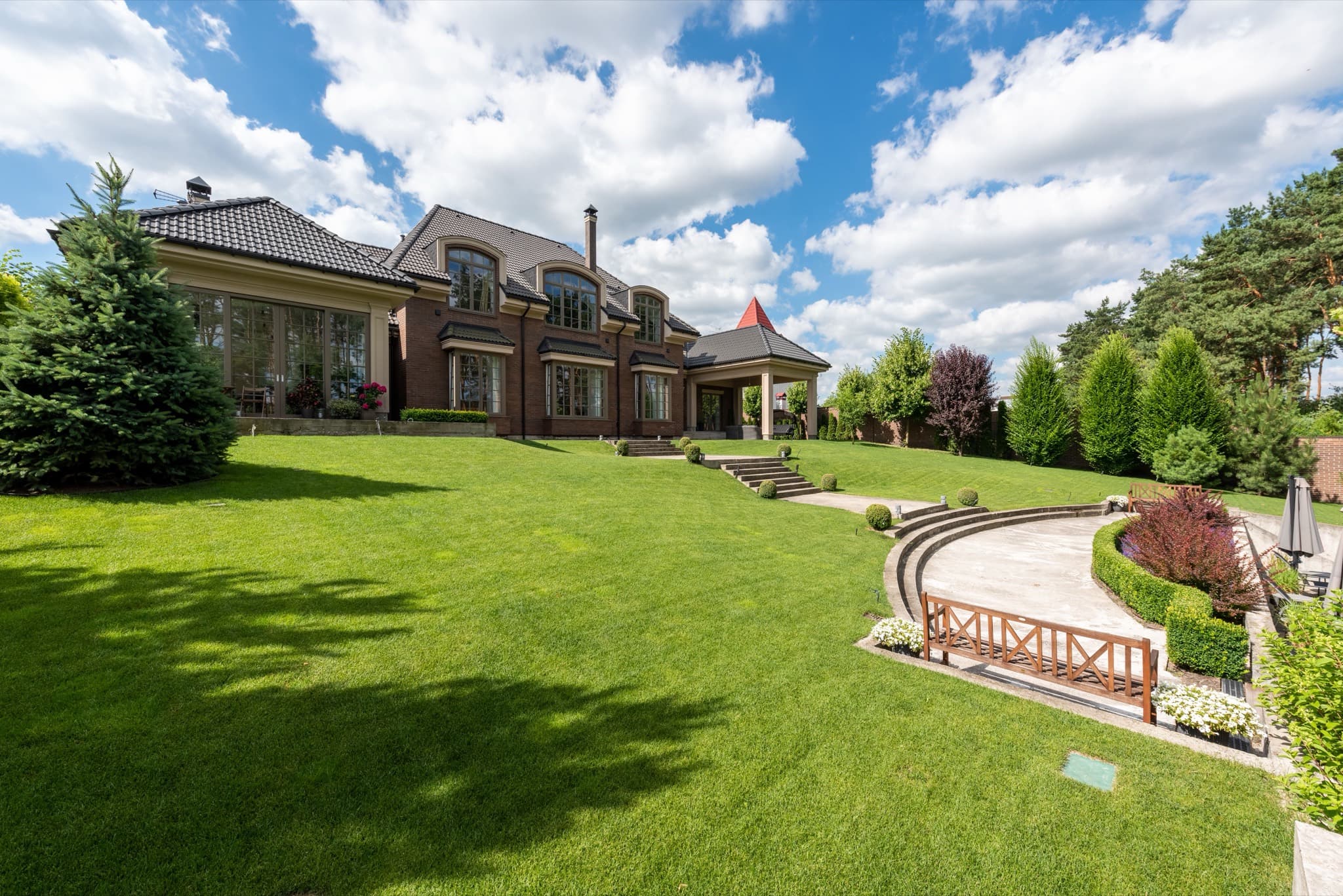 Brick home above a broad lawn with terraced garden steps and clipped hedges