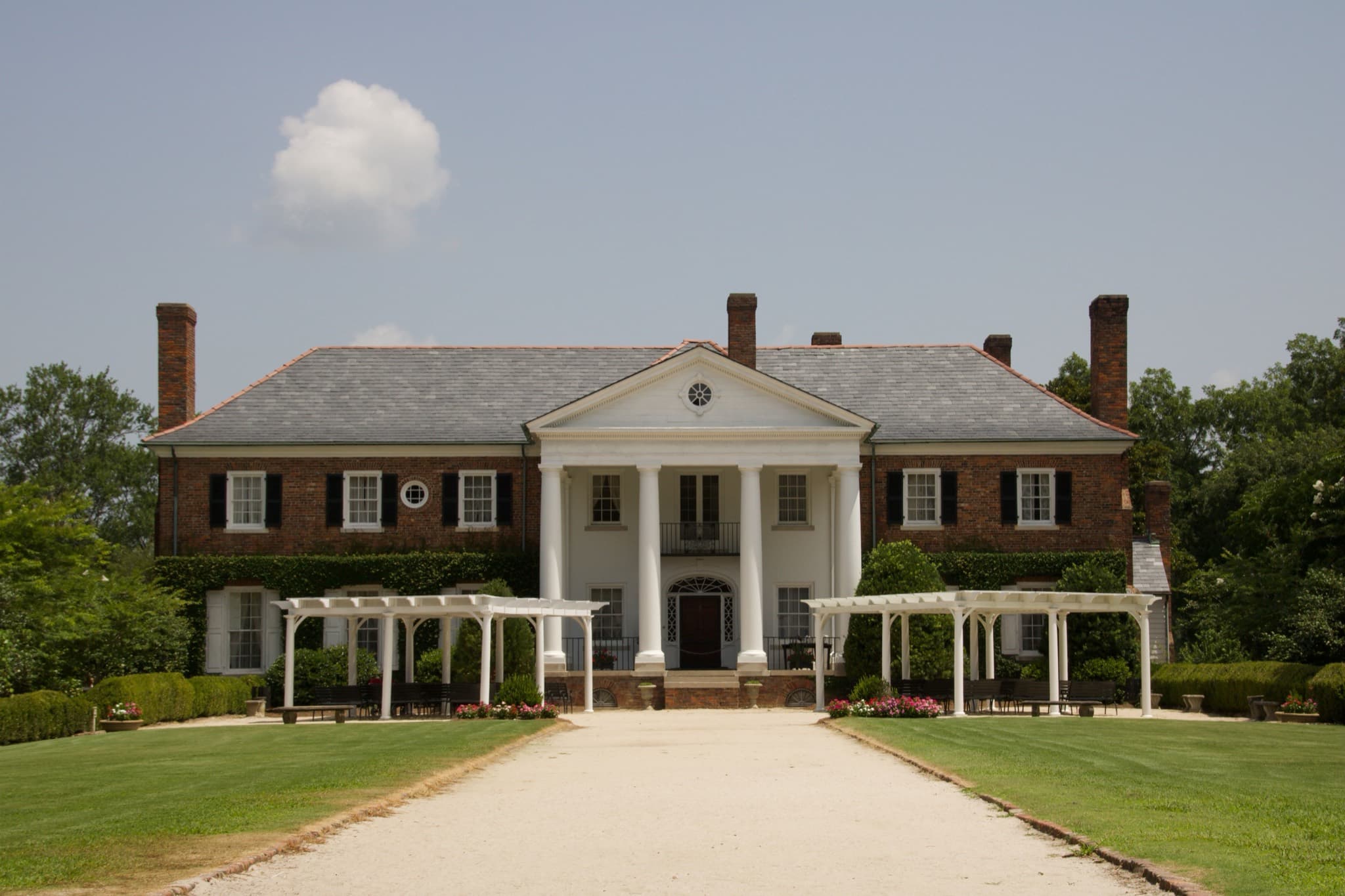 Brick Georgian estate house with a columned portico and a long gravel drive