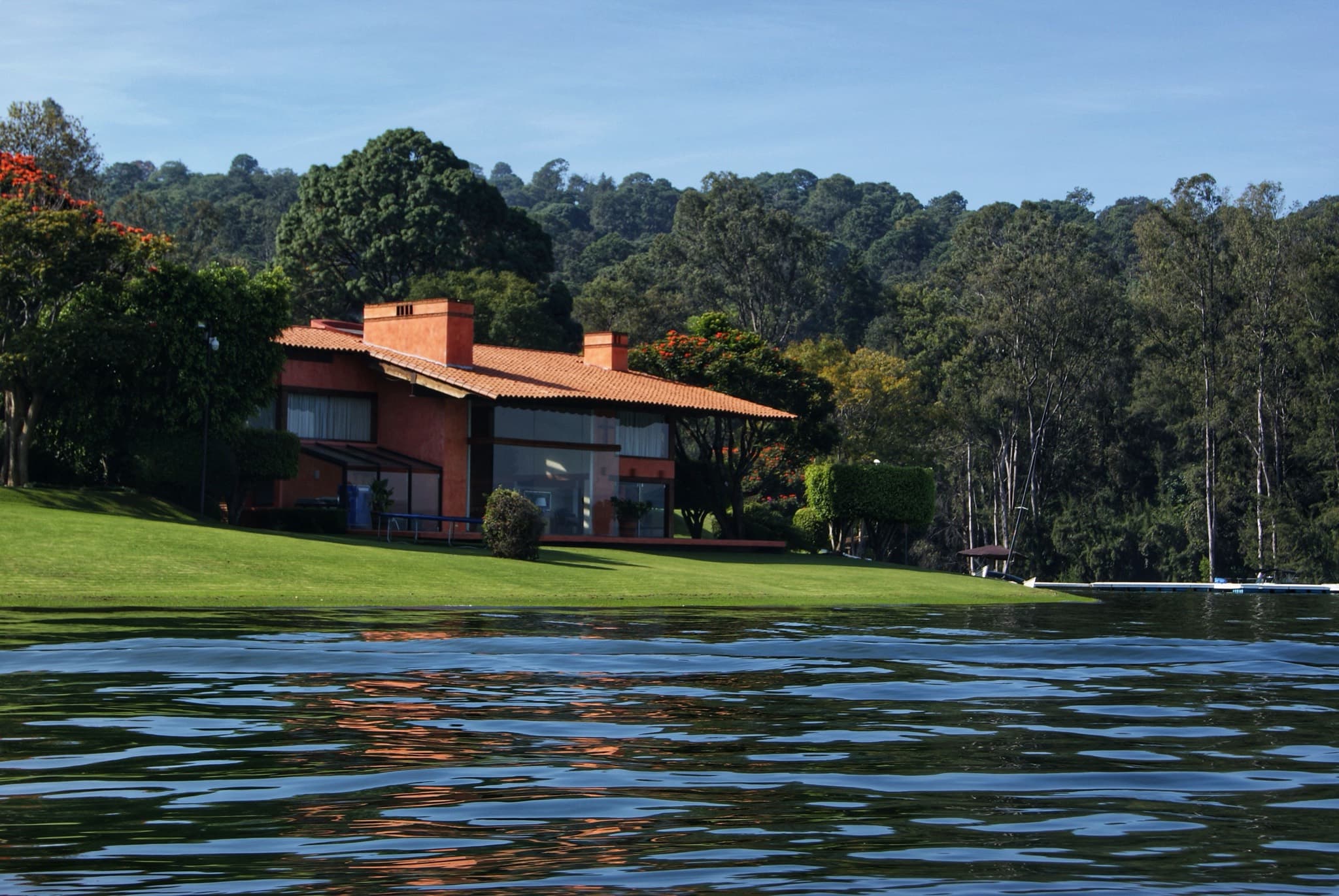 Lakefront house with a lawn running down to the water, backed by wooded hills