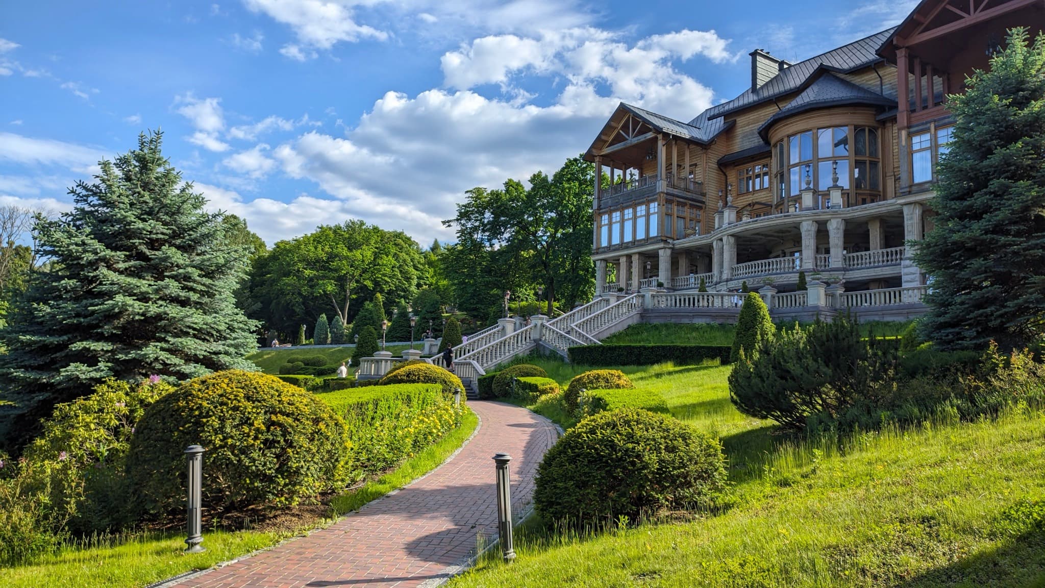 Large hillside home with terraces, stone steps, and landscaped gardens